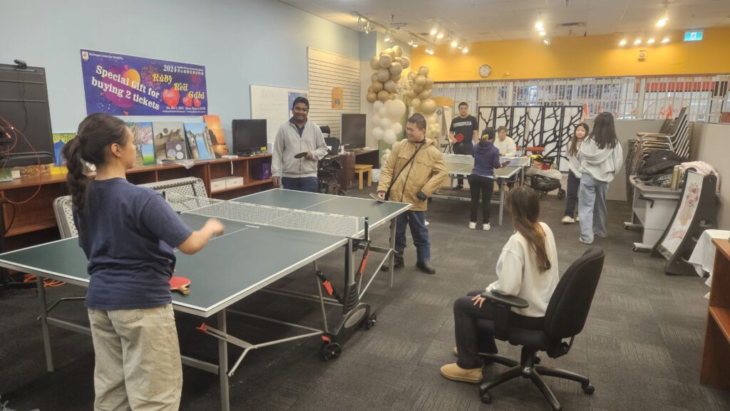 Lots of people hanging out and playing table tennis.